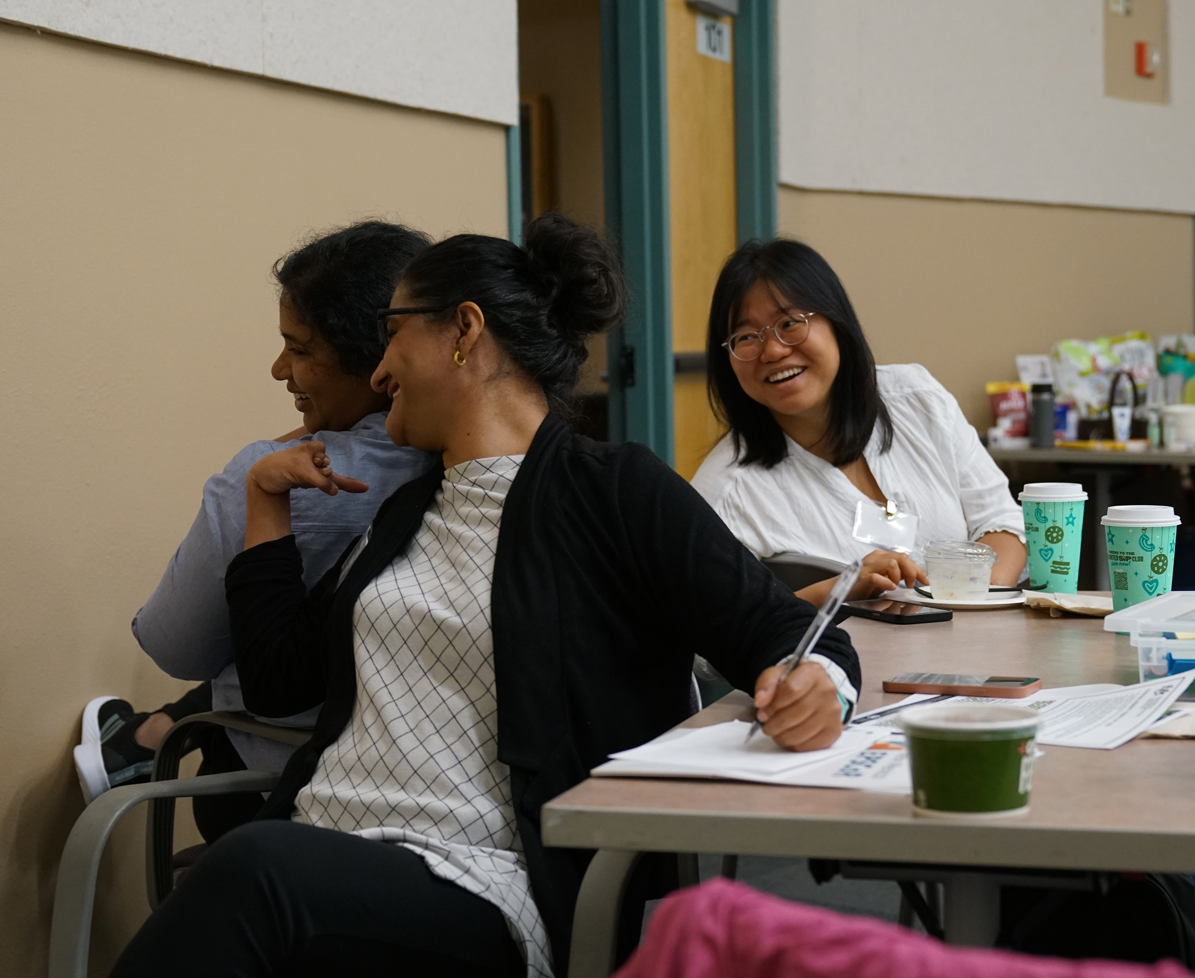 three women smiling while doing an activity at the workshop
