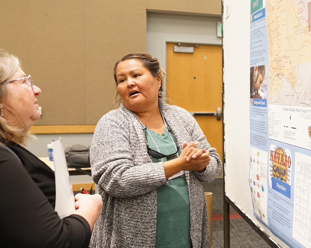 woman at research conference explaining results of poster