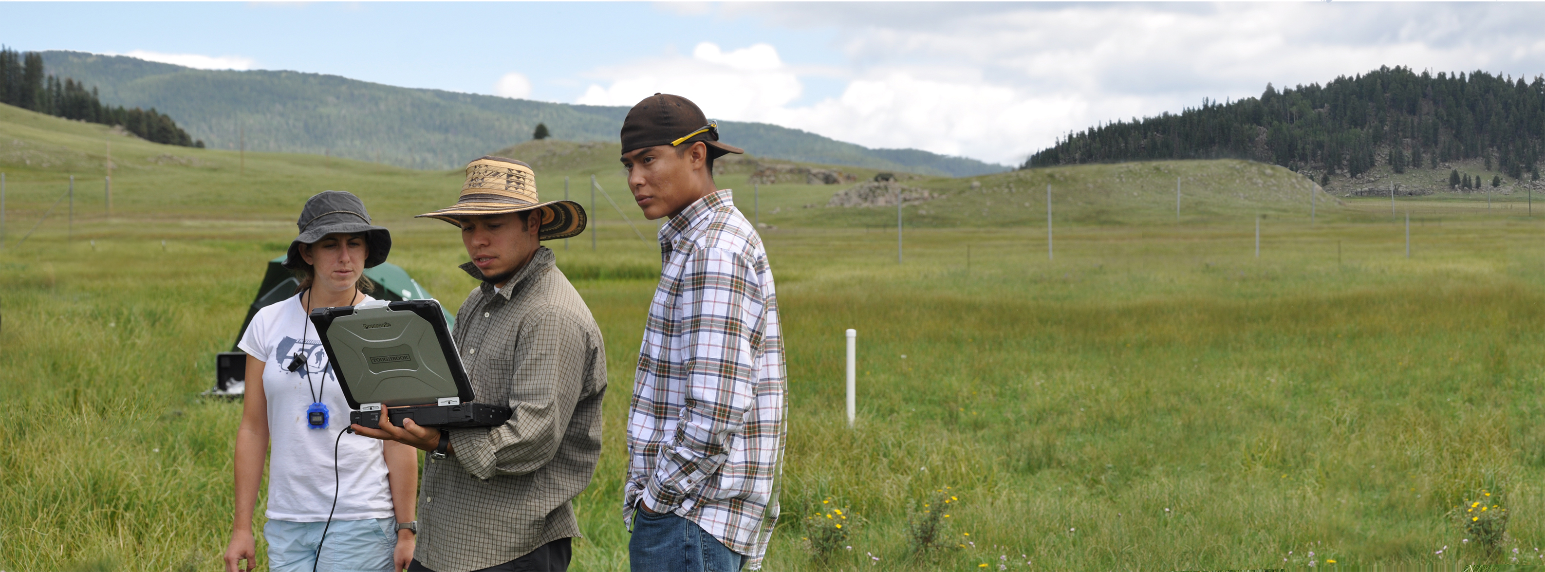 researchers standing in the valle grande looking at computer