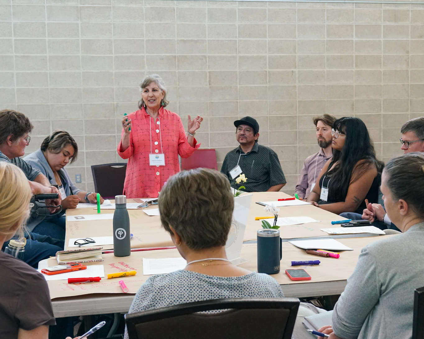 woman directing discussion at a table with many people