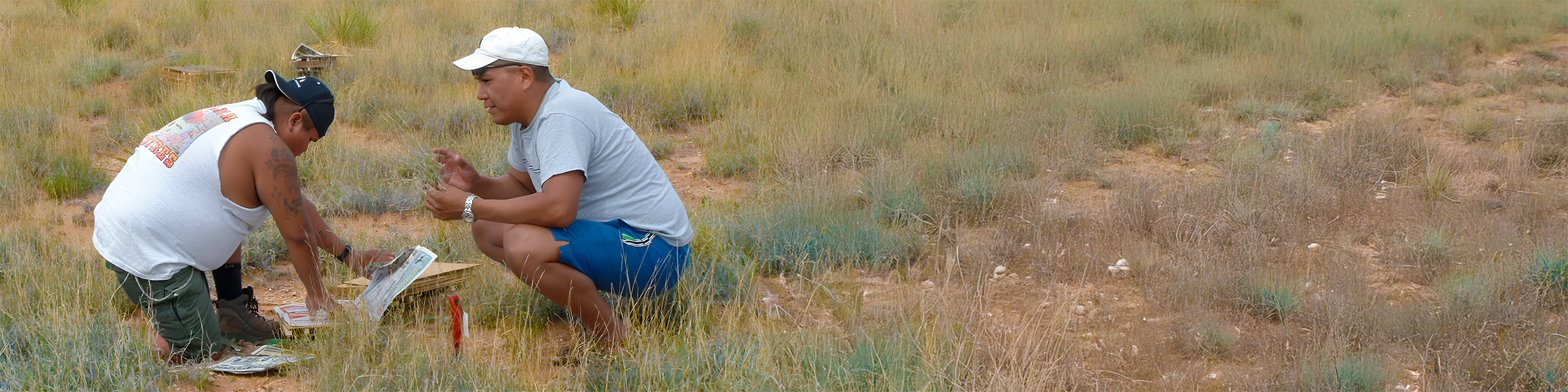 two men sitting in a grassland